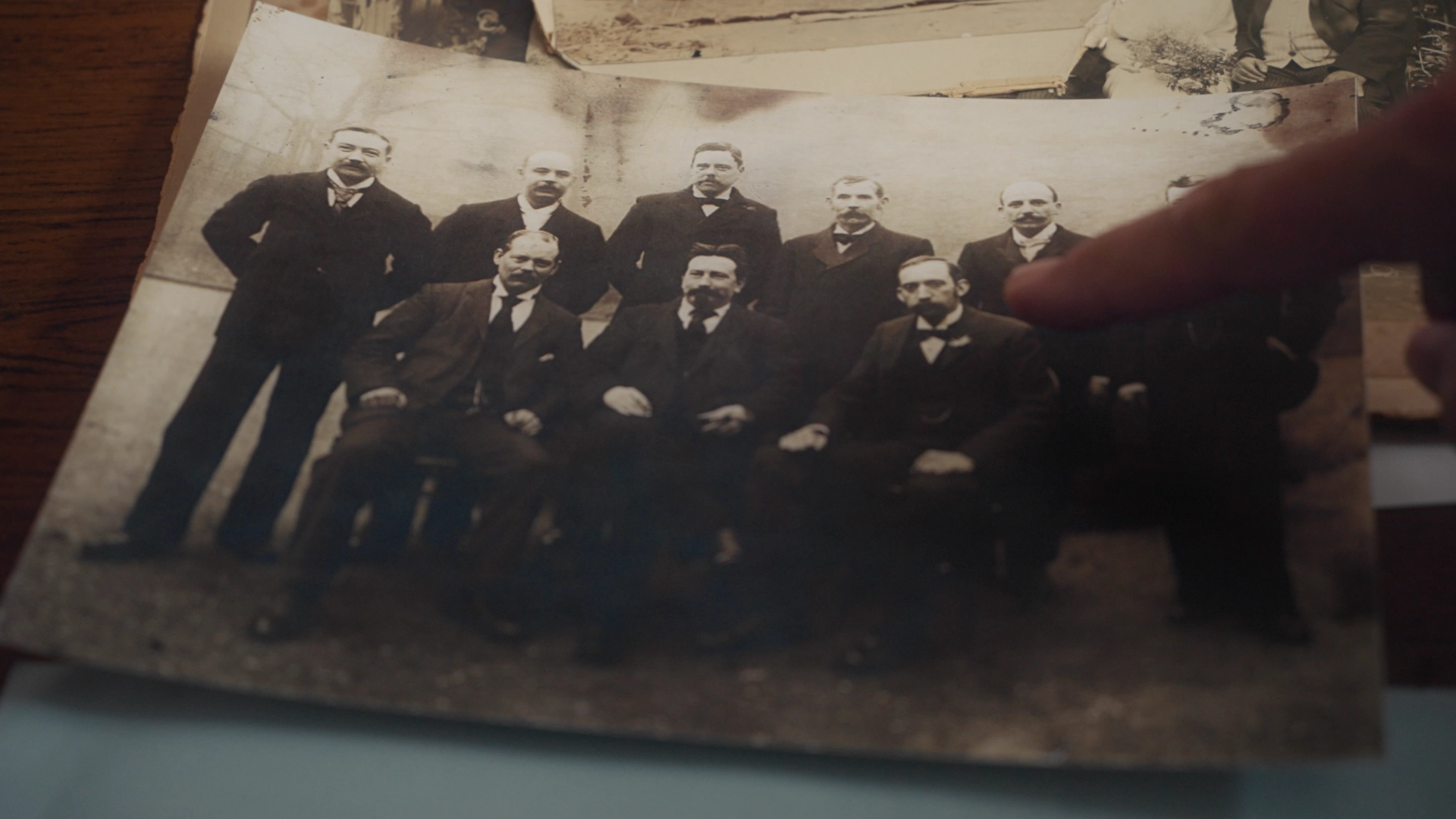 A finger pointing at an old sepia group photograph of Edwardian men, from Dear Mr Manley