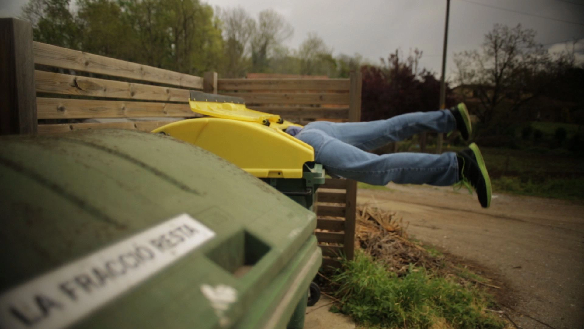 A person diving headfirst into a yellow-lidded recycling bin, from Yoghurt Utopia